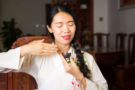 Asian girl enjoying a fresh cup of tea at homeの写真素材