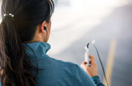 Girl jogging with earphones and listening to music, city runningの写真素材