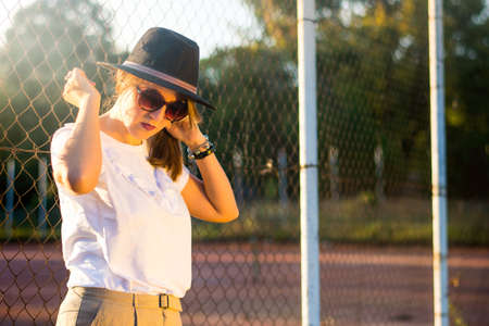 Portrait of a fashionable woman in the park at sunset