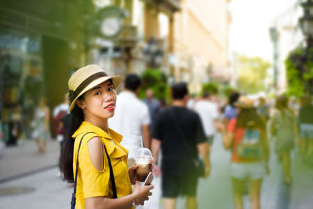 Asian girl on the street with coffee to goの写真素材