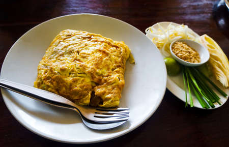 Egg wrapped pad thai served on a plate in restaurantの写真素材