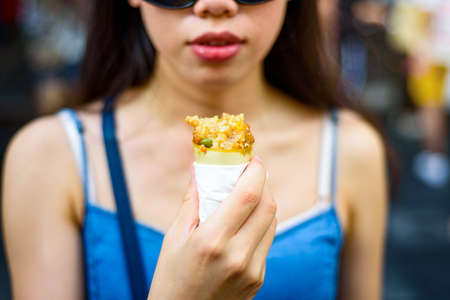 Girl eating Chicken wing snuffed with rice in the street