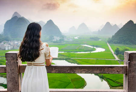Girl reading book with nice mountain view in the natureの写真素材