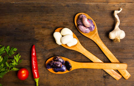 Natural white beans in wooden spoons on a table top view