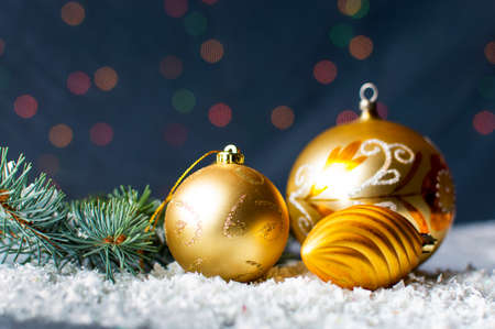 Golden Christmas ornaments and fir branch with festive backgroundの写真素材