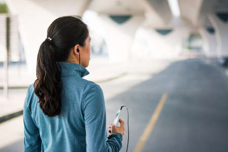 Girl jogging with earphones and listening to music, city running