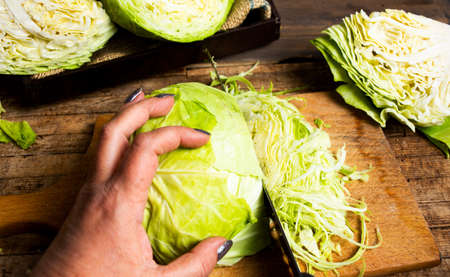 Woman cutting cabbage on a table closeup