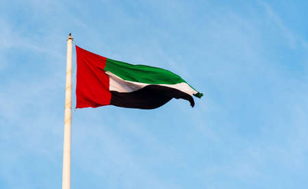 United Arab Emirates flag winding in the wind against blue skyの写真素材