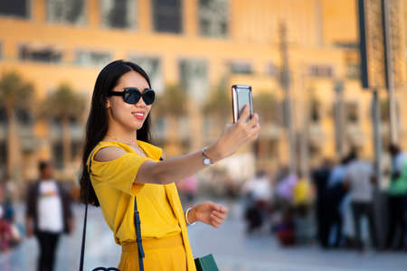 Happy Asian tourist taking selfie at Dubai mallの写真素材