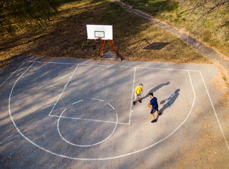 Father and son playing basketball in the park aerial view