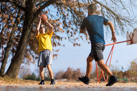 Senior father and son playing basketball in the park