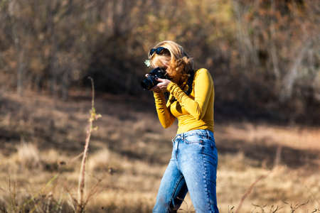 Fashionable girl taking photos outdoors on a hiking tripの写真素材
