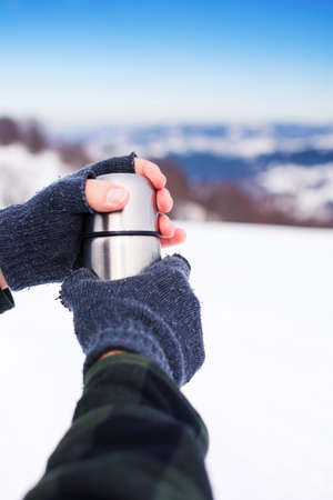 Man using thermos bottle on the snowy mountainの写真素材