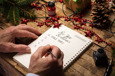 Old man making a list of new year resolutions on a decorated tableの写真素材