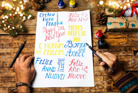 Person writing a Happy new year card in various languages