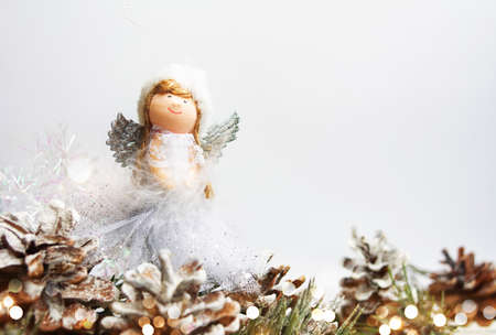 Toy angel and Christmas background with pinecones and fir tree