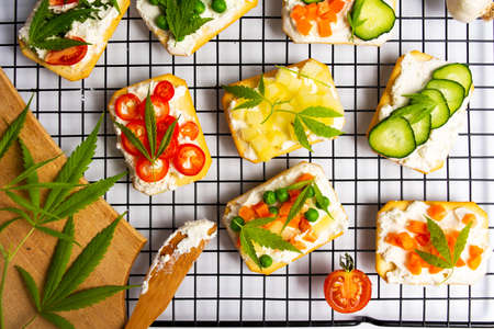 Sandwiches with marijuana leafs and vegetables on a grid top viewの写真素材