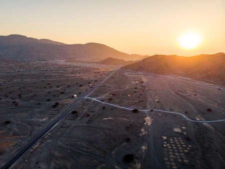 Desert road surrounded by rocks at sunset aerial view