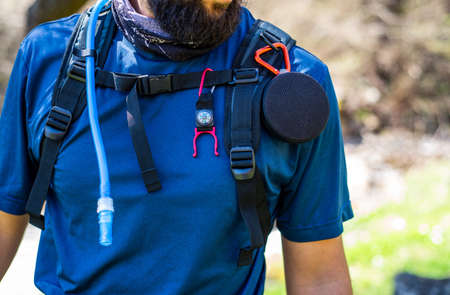 Equipped hiker with speaker, compass and water pipe close up