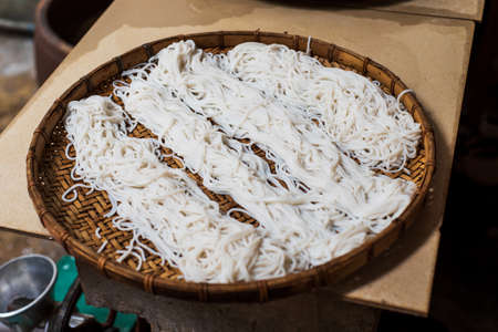 Homemade noodles on a bamboo plate ready for cookingの写真素材