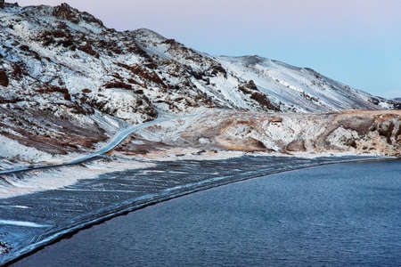 Kleifarvatn lake in Iceland on a winter day with scenic road covered in snow
