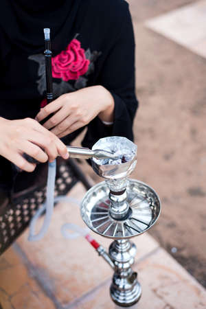 Muslim woman smoking hookah in a coffee bar