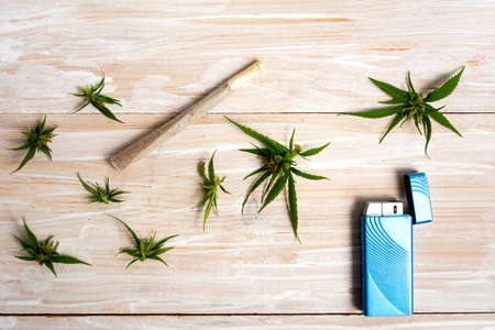 Marijuana plant with buds and joint on a wooden tableの写真素材
