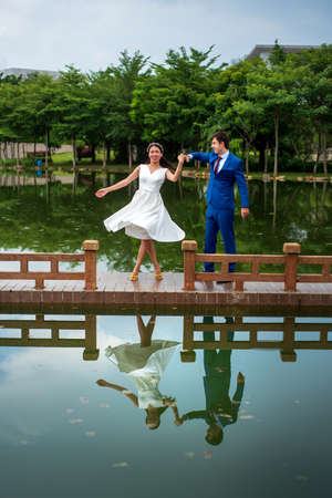 Romantic couple dancing by the lake reflected in the waterの写真素材