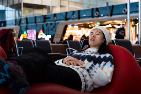 Girl taking a nap while waiting at the airport loungeの写真素材