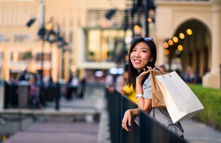 Happy woman with shopping bags standing in front of a mallの写真素材