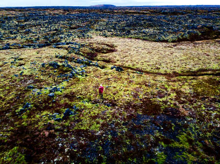 Woman standing in green lava fields in south Iceland aerial viewの写真素材