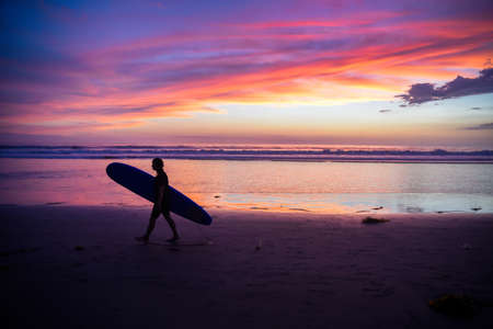 Surfer silhouette carrying a surfboardの写真素材