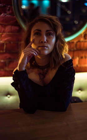 blonde girl posing in front of a brick wall with warm yellow light indoorの写真素材