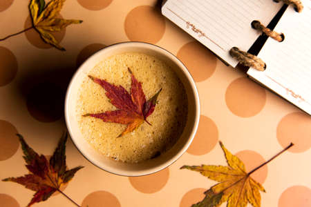 Coffee with autumn leaf on a table top viewの写真素材