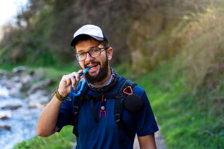 Man hiking by the river and hydrating with water pipeの写真素材