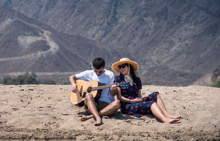 Couple singing and playing guitar buy the beach on summer vacationの写真素材