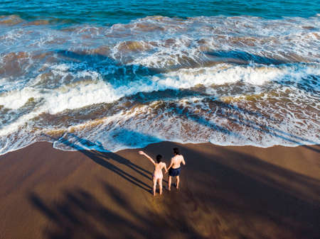 Couple holding hands on the beach aerial viewの写真素材