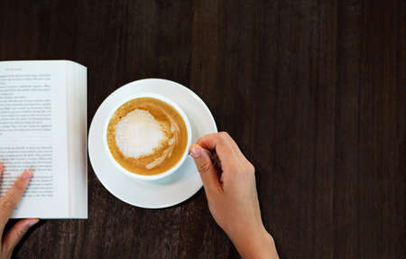 Girl having coffee in the bar and reading a book