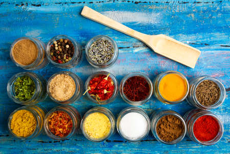 Large collection of spices in bowls on wooden table flat lay