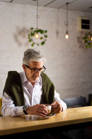 Senior man having a cup of coffee in the barの写真素材