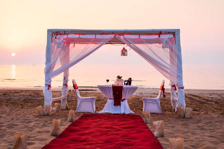Cabana and romantic dinner setting on a beach at sunsetの写真素材