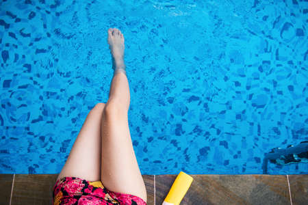 Girl with sun lotion at the swimming pool top view with copy spaceの写真素材