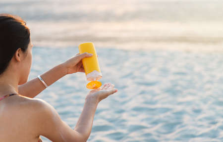 Woman using sun lotion on beach summer vacation