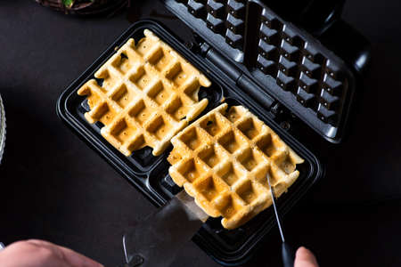 Waffles baking on a waffle maker close upの写真素材