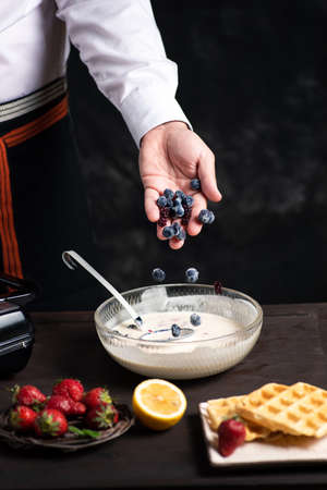 Chef adding fruit in waffles dough close upの写真素材