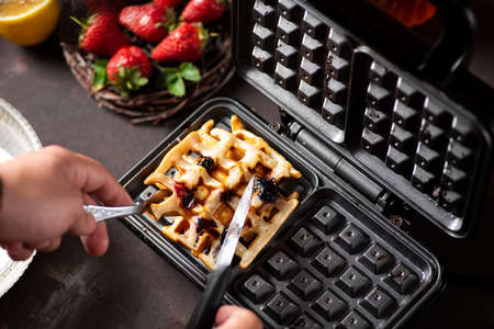 Man making waffles on a waffle machine close upの写真素材