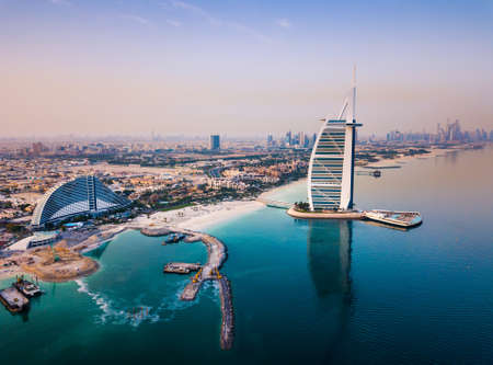 Burj Al Arab luxury hotel and Dubai marina skyline in the background at sunrise