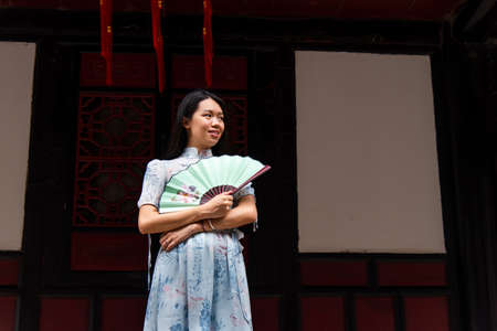 Asian woman in a temple holding a hand fan portrait