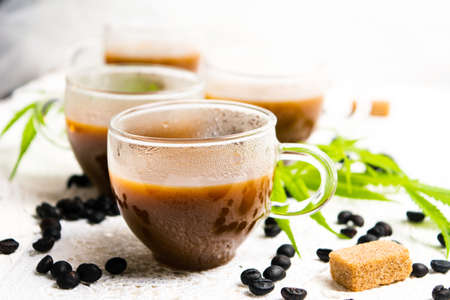 Cups of coffee with marijuana and roasted beans on a tableの写真素材