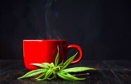 Cup of tea with marijuana cannabis leaves on dark backgroundの写真素材